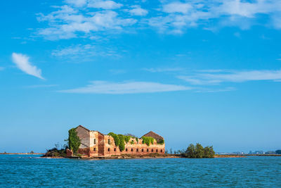 Buildings at waterfront against cloudy sky