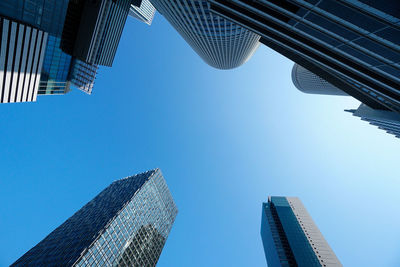 Low angle view of skyscrapers against blue sky