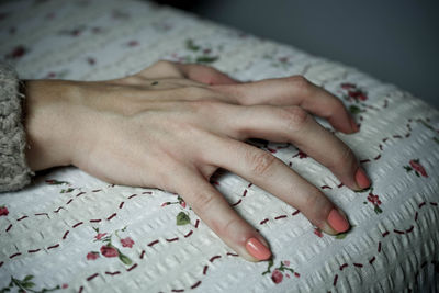 Close-up of woman touching hand on bed