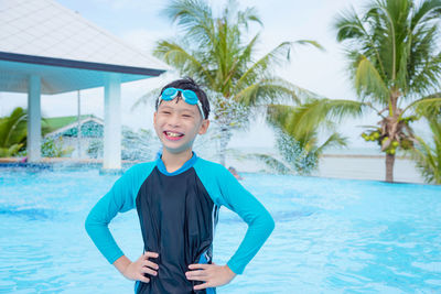 Smiling boy with hands on hip posing in swimming pool