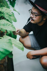 Young man looking away while sitting outdoors