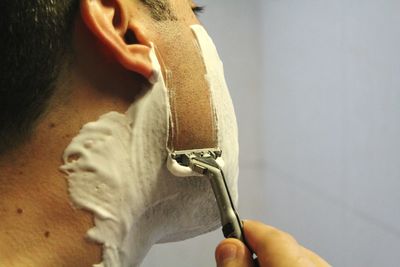 Midsection of man shaving in bathroom