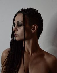Portrait of young woman looking away against wall with afro braids