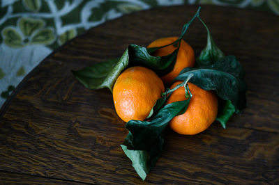 Clementines with leaves on wood cutting board