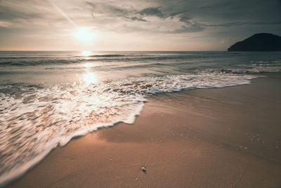 Long exposure shot soft wave of the sea on the sandy beach at morning sunlight, nature landscape 