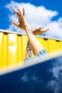 Cropped hand of woman against sky