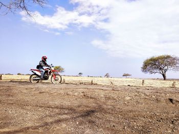 Horse riding bicycle on land against sky