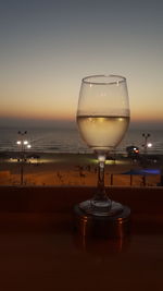 Close-up of beer on table against sea during sunset