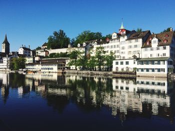 Buildings by river against blue sky