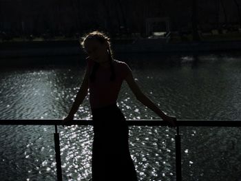 Woman standing on railing at night