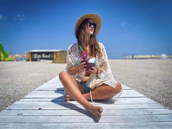 Fashionable young woman on the beach holding a cocktail in her hand