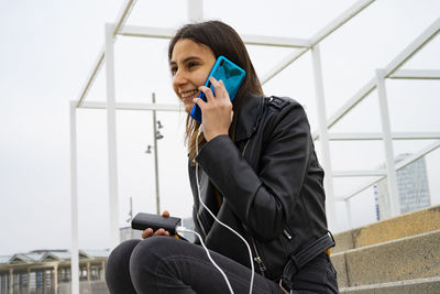 Woman talking on the phone while charging her mobile with a powerbank.