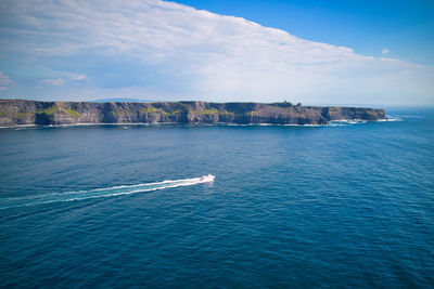 Aerial view of a speedboat ferry below cliffs of moher. 