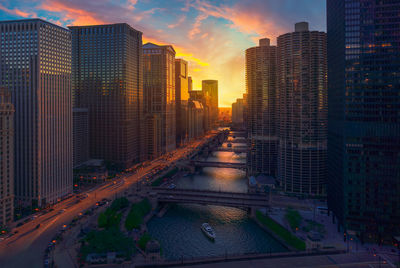 City street amidst buildings against sky during sunset