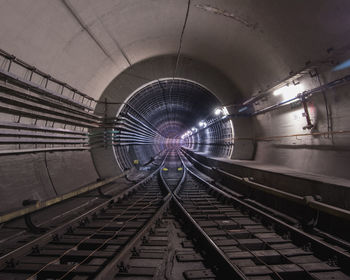 Railroad tracks in illuminated tunnel