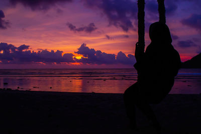 Silhouette man on beach against sky during sunset