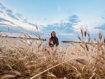 Portrait of young woman standing on field against sky