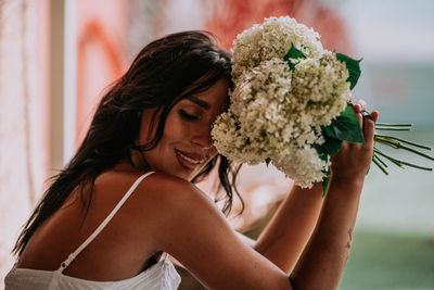 Portrait of a beautiful young woman holding red flowering plant