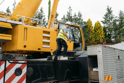 Operator climbing on construction crane lifting heavy freight. modern mobile transportation