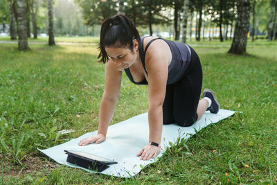 A charming brunette woman plus-size body positive practices sports in nature.