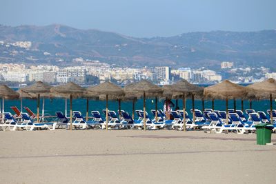 Lounge chairs and parasols at malaga beach against mountains