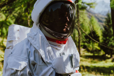 Close-up of man wearing spacesuit against trees