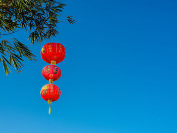 Low angle view of lanterns hanging against clear blue sky