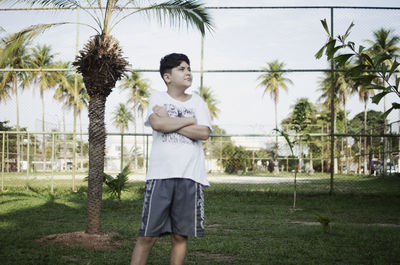 Young man looking away while standing on palm tree