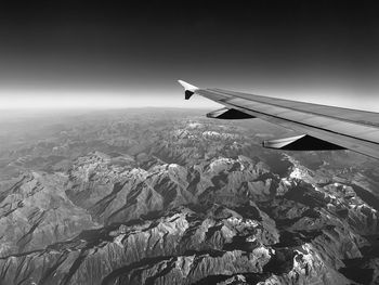 Airplane flying over rocks against sky