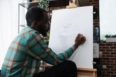 Rear view of artist sketching on canvas