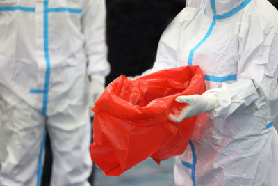 Midsection of doctors holding garbage bag
