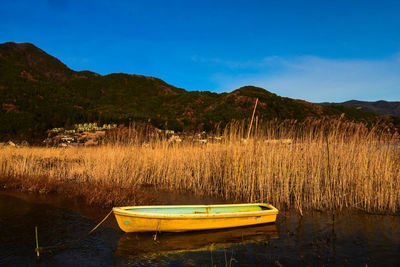 Boats moored on lake against blue sky