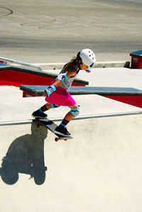 Full length of girl skateboarding on sports ramp during sunny day