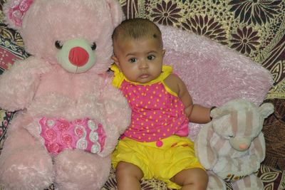 Portrait of cute baby girl sitting on bed