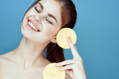 Close-up of woman eating food against blue background