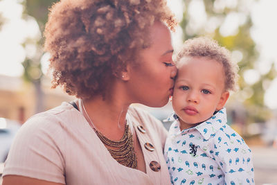 Mom holding and kissing her baby boy, baby looking at camera