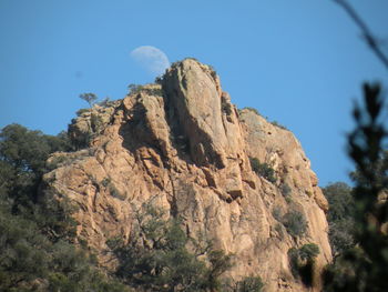 Low angle view of rocky mountain against blue sky