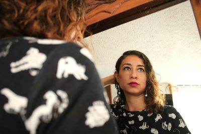 Low angle view of young woman reflecting in mirror at home