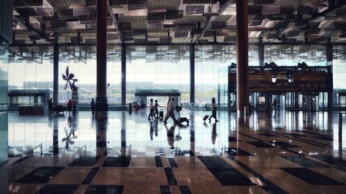 People walking in airport seen through glass window