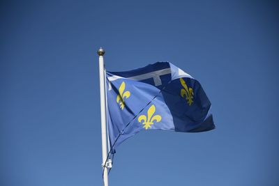 Low angle view of flags against clear blue sky