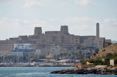 Buildings by sea against sky