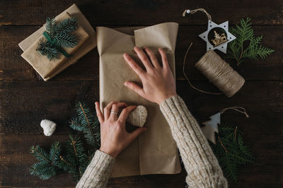 Christmas wrapping idea, xmas wrapping workspace. female hands wrap gift box in kraft 