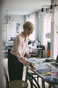 Woman standing at table working at home