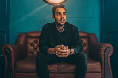 Young man using mobile phone while sitting on sofa