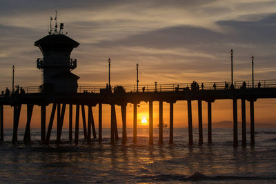 Silhouette pier over sea against sky during sunset