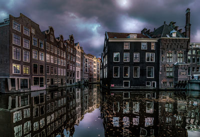 Reflection of buildings in canal against sky