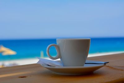 Close-up of coffee cup on table against sea