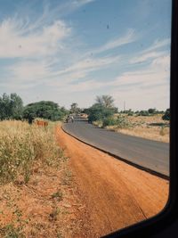 Road amidst field against sky