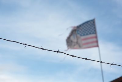Low angle view of barbed wire fence against american flag