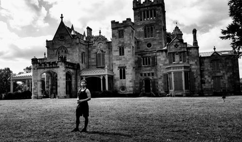 Portrait of handsome young man standing against old church while standing on field